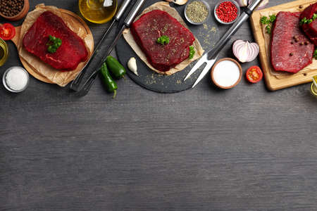 Concept of cooking with raw steak on wooden background