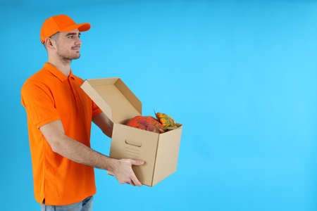 Delivery man holds box with pumpkins on blue backgroundの写真素材
