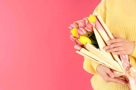Woman holding bouquet of flowers on pink backgroundの写真素材