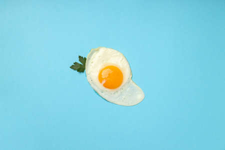 Fried egg with spices on blue background, top view