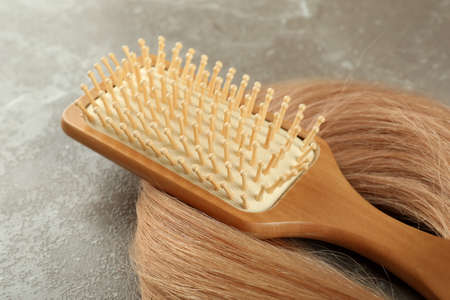A lock of female hair with hairbrush on gray textured backgroundの写真素材