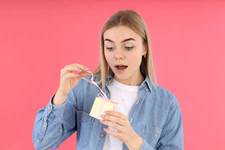 Young woman with gift box on pink backgroundの写真素材