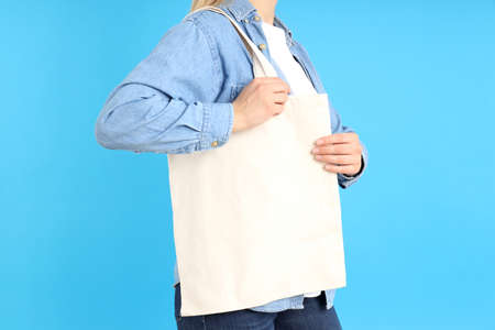 Woman holding white eco bag on blue background