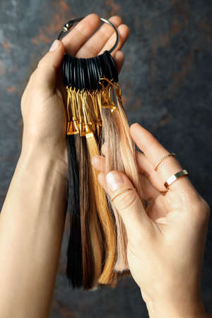 Female hand holds hair samples on dark backgroundの写真素材