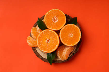Board with tangerine and leaves on orange backgroundの写真素材