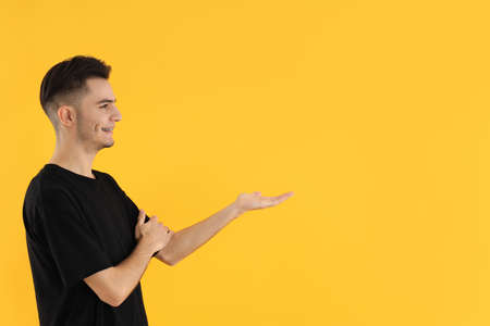 Attractive young man in t-shirt on yellow backgroundの写真素材