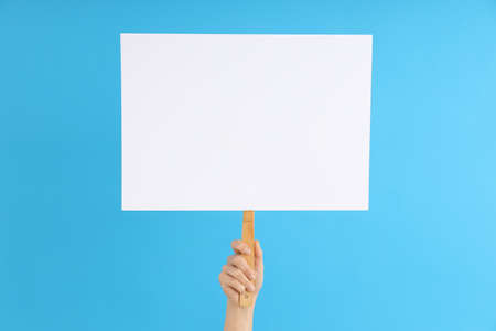 Female hand holding protest sign on blue background