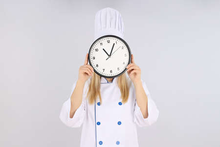 Female chef with clock on light backgroundの写真素材