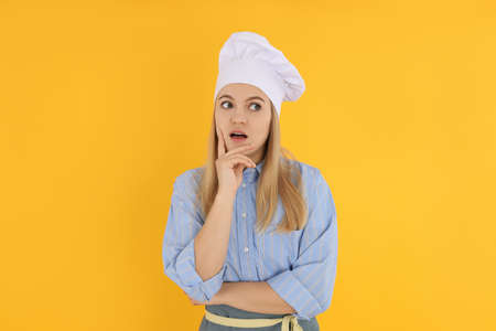 Young housewife or chef on yellow background