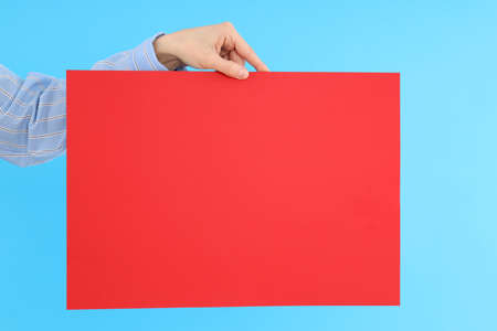 Female hand holding blank banner on blue backgroundの写真素材