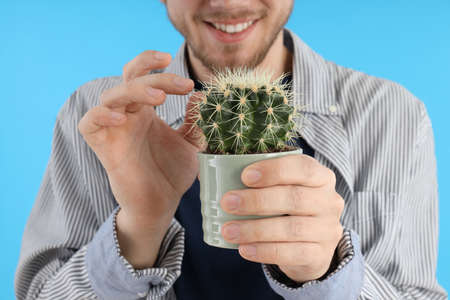 Young man holds cactus plant, close upの写真素材