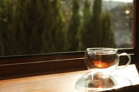 Cup of tea stands on wooden windowsillの写真素材