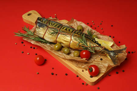 Concept of tasty food, smoked mackerel on red background