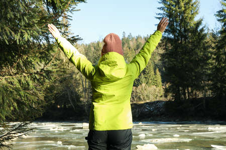 Woman with spread hands standing near the river