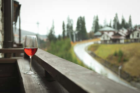 Glass of wine on wooden balcony in ski resortの写真素材