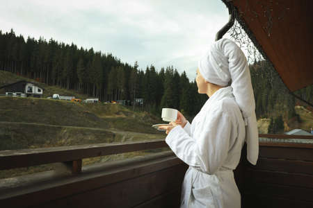 Woman with cup of coffee on balcony in ski resortの写真素材
