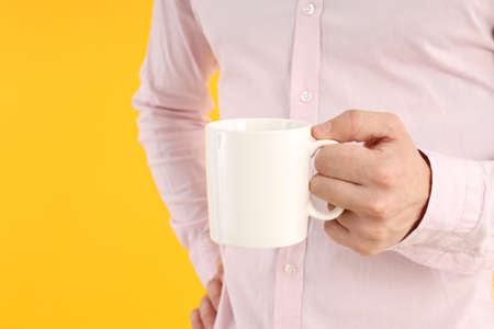 Man holds cup on yellow background, space for text