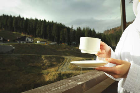 Woman with cup of coffee on balcony in ski resortの写真素材