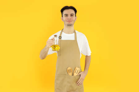 Concept of cooking, young man chef on yellow background