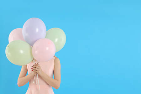 Concept of Happy Birthday, young woman with balloons on blue backgroundの写真素材