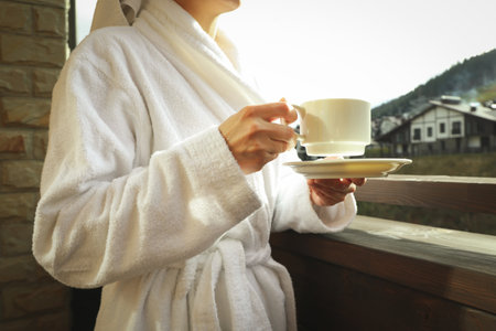 Woman with cup of coffee on balcony in ski resortの写真素材
