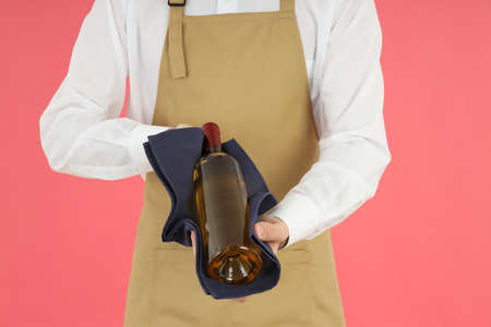 Male waiter holding wine on pink backgroundの写真素材