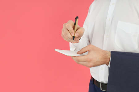 Male waiter writes order on pink backgroundの写真素材