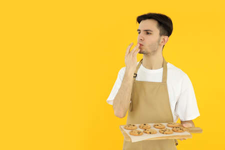 Concept of cooking, young man chef on yellow background