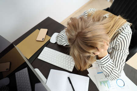 Young tired business woman sitting on workplace