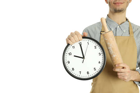 Young man in apron with clock and rolling pin isolated on white backgroundの写真素材