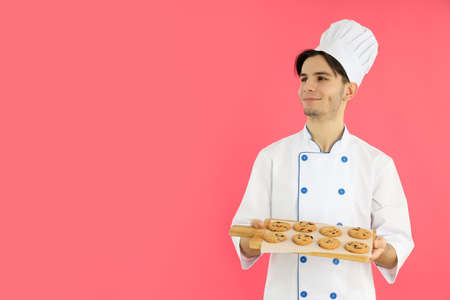 Concept of cooking, young man chef on pink backgroundの写真素材
