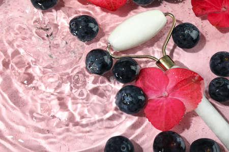 Blueberry, face roller and flowers in water