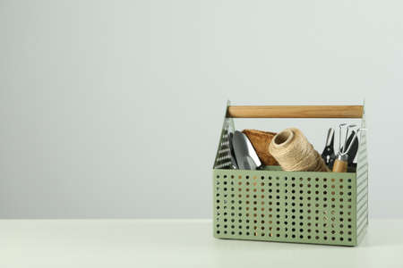 Gardening tools and accessories on white table against light gray background