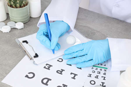 Female doctor writes in clipboard on workplace table