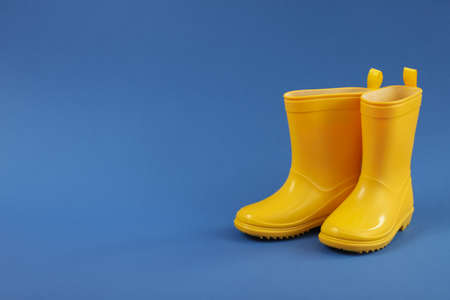Rubber boots on blue background, space for text