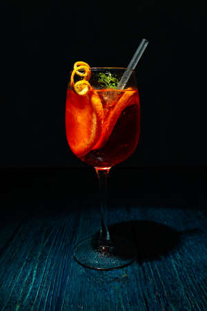 Concept of fresh summer cocktail, Aperol Spritz on wooden table against dark background