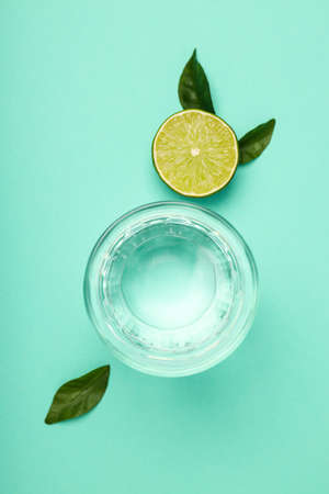 Glass of water, lime and leaves on mint backgroundの写真素材