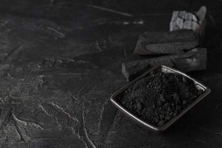 Natural hardwood charcoal on black textured backgroundの写真素材