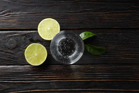 Glass of water, lime and leaves on wooden backgroundの写真素材