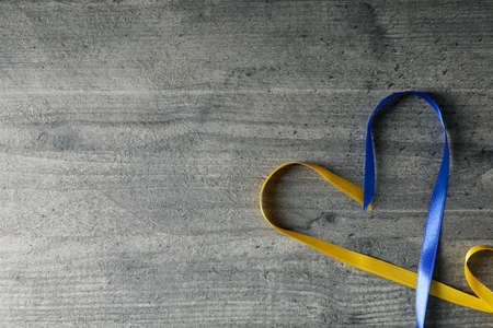 Heart made of ribbons in Ukrainian flag colors on gray wooden backgroundの写真素材