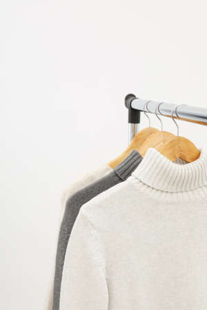 Wardrobe rack with hangers with sweaters on light backgroundの写真素材