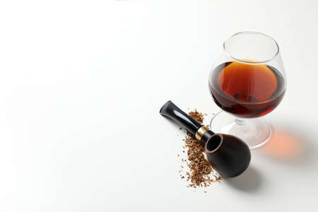 Glass of alcohol, smoking pipe and tobacco on white backgroundの写真素材