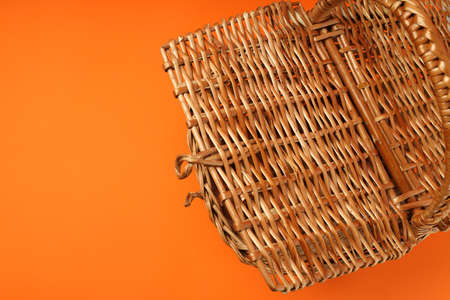Wicker basket for picnic on orange background