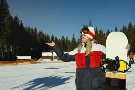 Happy young woman with snowboard in mountain resortの写真素材