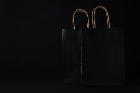 Black paper bags on black background, space for textの写真素材
