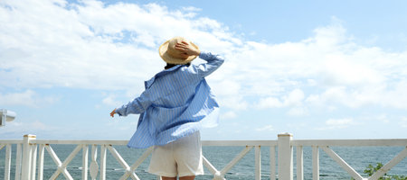Young woman standing near the sea in sunny summer dayの写真素材