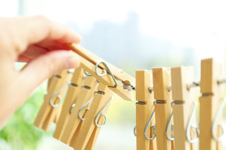 A woman's hand holds a clothespin on a twine, close upの写真素材