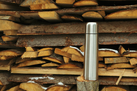 Casual steel flask standing outdoor near firewood