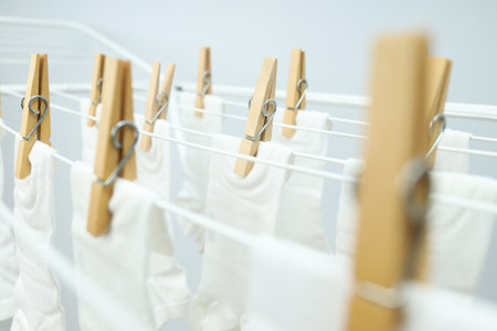 White socks hanging on drying rack on light backgroundの写真素材