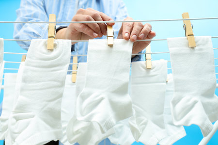 White socks hanging on drying rack on blue backgroundの写真素材